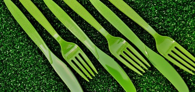 Green plastic cutlery on green grass