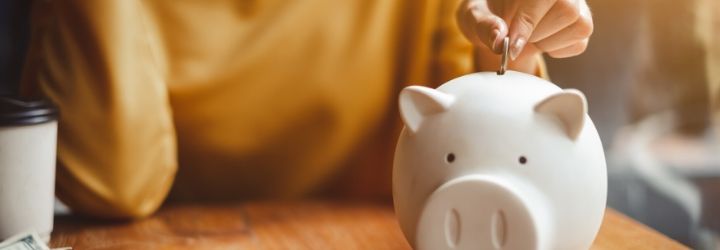 Woman in the background putting a coin into a pig-shaped piggy bank.