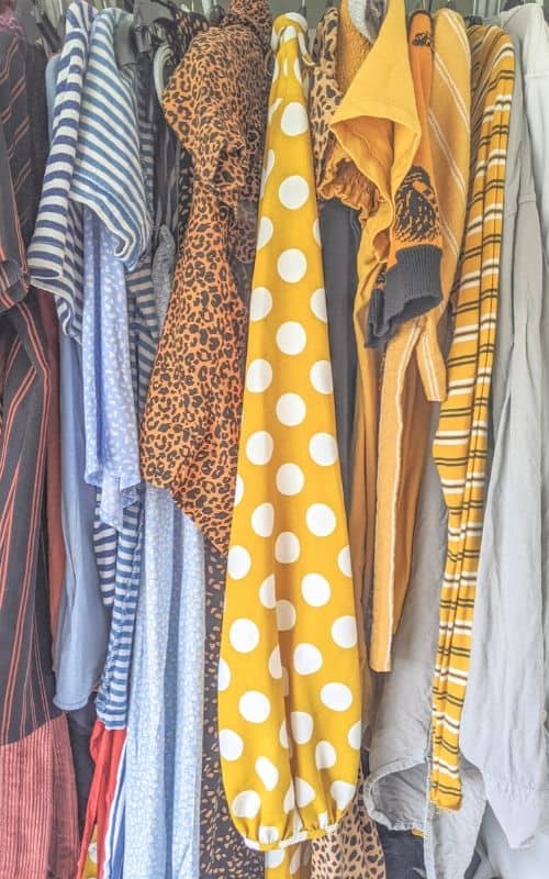 Sell clothes online: colourful clothes hanging next to one another. A yellow sleeve with white polka dots dominates the middle of the photo.