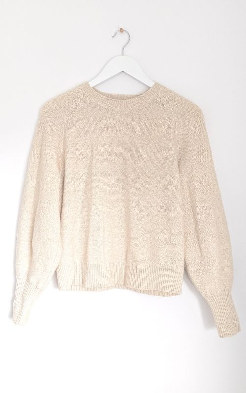 Sell clothes online with good photos: cream jumper on a white hanger against a white wall in natural light.