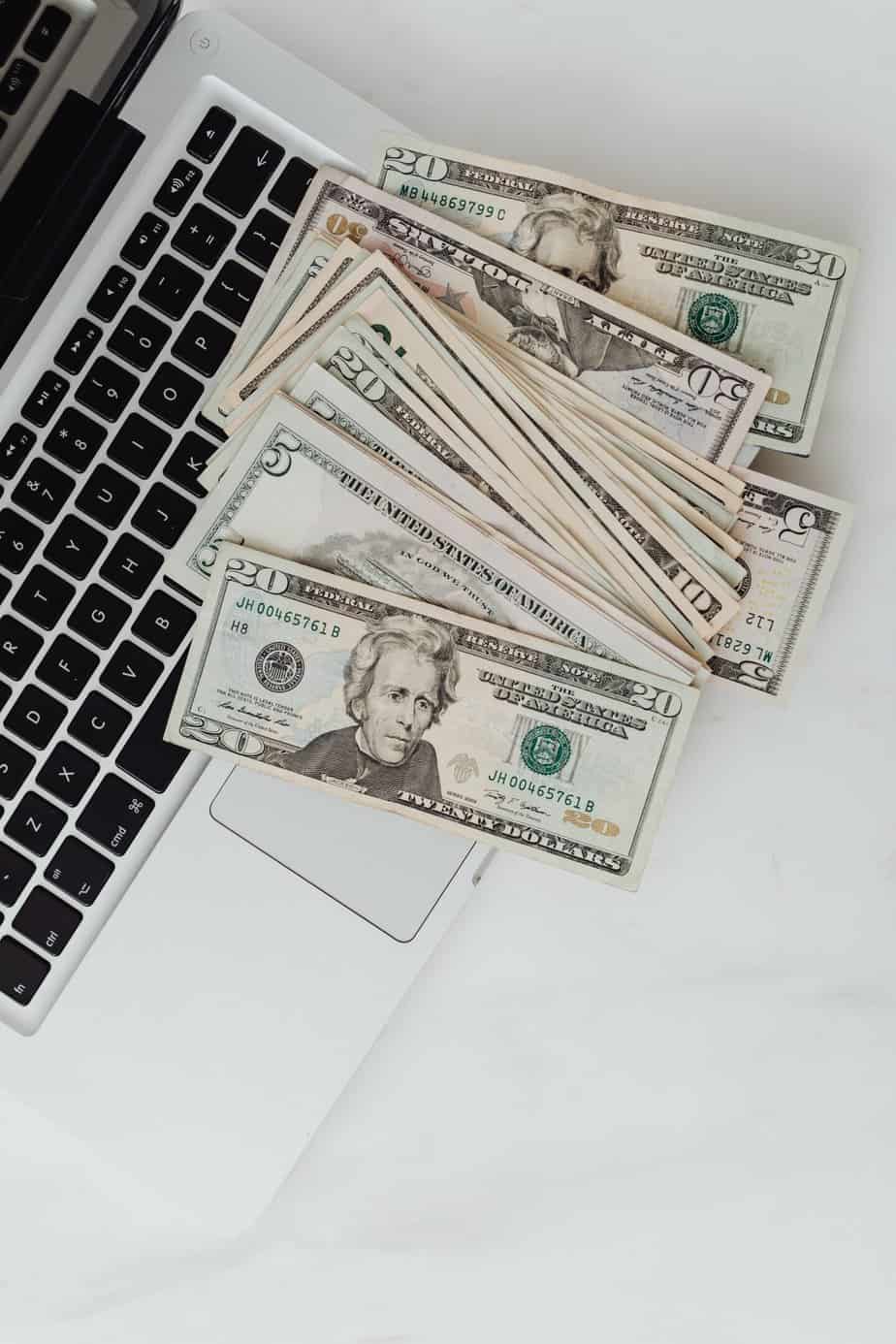 how to make $300 fast: a laptop with cash notes on top of it.